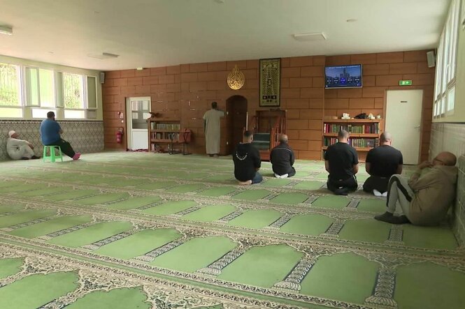 EIne Moschee von innen, grüner Teppich, betende Menschen