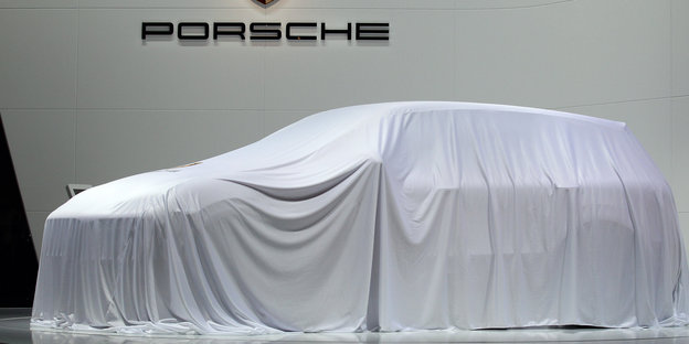 Ein mit einer Decke abgedecktes Auto. Darüber der Schriftzug „Porsche“.