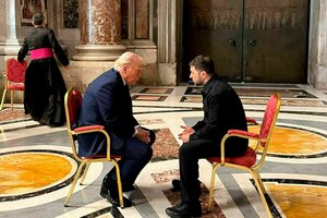 Trump und Selenskji sitzen auf zwei Stühlen vor sakraler Kulisse und unterhalten sich