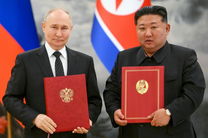 Wladimir Putin und Kim Jong Un posieren mit roten Mappen in der Hand