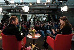 Zu sehen ist Luisa Neubauer, Klimaaktivistin, im Gespräch mit taz FUTURZWEI Chefredakteur Peter Unfried. Im Hintergrund Publikum.