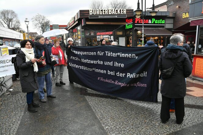 Teilnehmende einer Mahnwache halten im Stadtteil Neukölln ein Transparent mit dem Aufdruck „Konsequenzen für Täter*innen, rechte Netzwerke und ihre Unterstützer*innen bei der Polizei! #Neukölln-Komplex auflösen“.