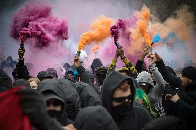 Bunte Pyrofackeln werden im schwarzen Block hochgehalten