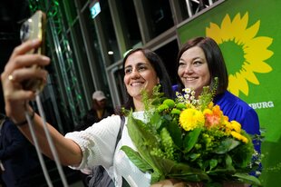 Maryam Blumehthal und Katharina Fegebank machen ein Selfie mit Blumentstrauß