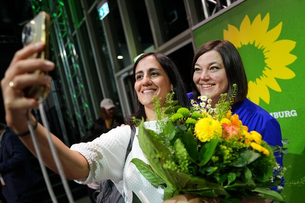 Maryam Blumehthal und Katharina Fegebank machen ein Selfie mit Blumentstrauß