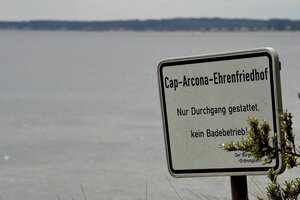 Ein Schild am Rand der Ostsee weist einen Strandabschnitt als Ehrenfriedhof aus, an dem Baden verboten ist