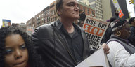 Demonstration in New York, in der Mitte ein weißer Mann in Lederjacke, Quentin Tarantino, links und rechts von ihm schwarze Frauen
