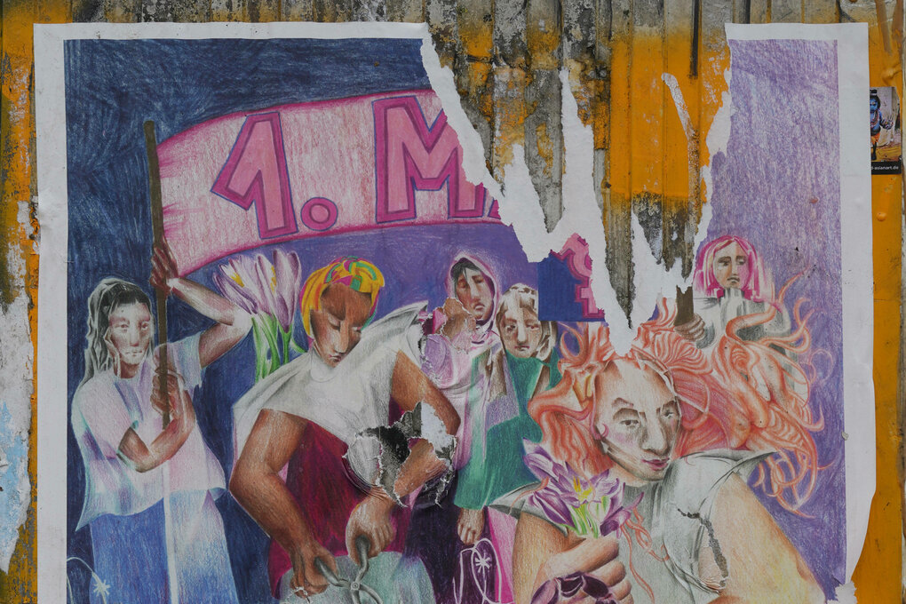 Ein zerrissenes Plakat an einer Hauswand, auf dem zum feministischen Block auf dem 1. Mai aufgerufen wird. Dargestellt ist eine Frau, die Stacheldraht durchtrennt