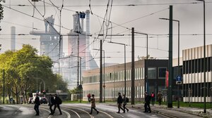 Menschen laufen im Gegenlicht über STraßenschienen, im Hintergrund raucht ein Stahlwerk