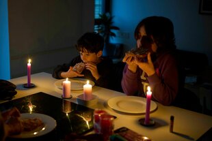 Mehrere Personen sitzen bei Kerzenlicht an einem Esstisch.