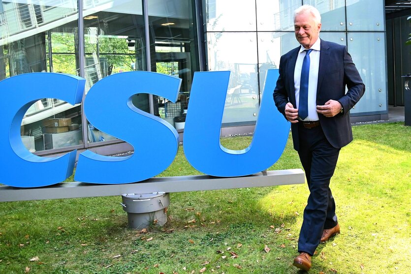 Ein Mann im Anzug geht an einem CSU Logo vorbei