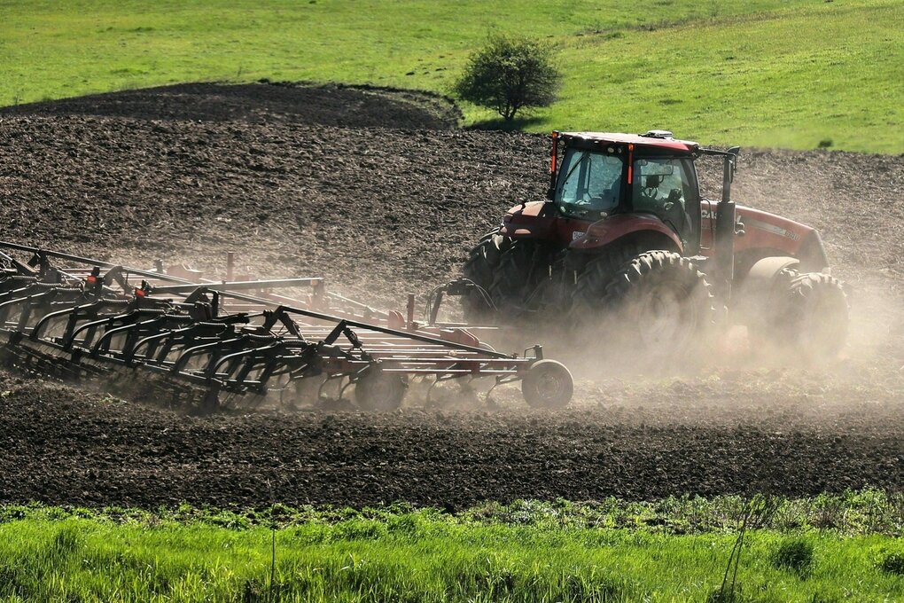 Ein Traktor bringt auf einem Feld Saatgut auf