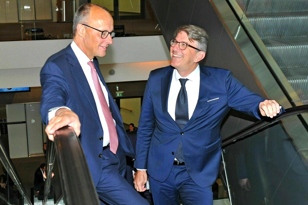 Zwei Männer in Anzügen stehen auf einer Rolltreppe