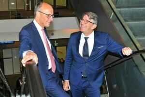 Zwei Männer in Anzügen stehen auf einer Rolltreppe