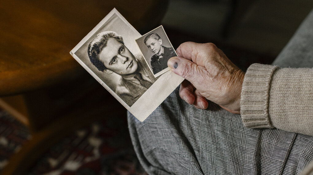 Eine Hand hält zwei alte Fotos von jungen Männern