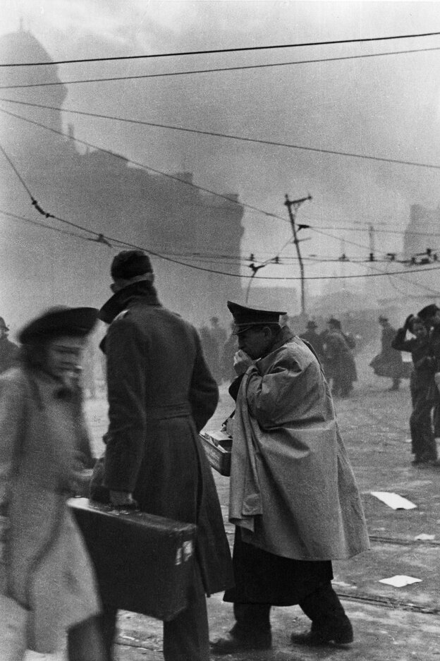 Eine historische Straßenszene: menschen laufen durcheinander, Rauch liegt in der Luft, ein Mann trägt einen großen Koffer