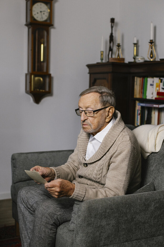 Hans-Jürgen Pickert blickt auf Fotos, die er in seinen Händen hält