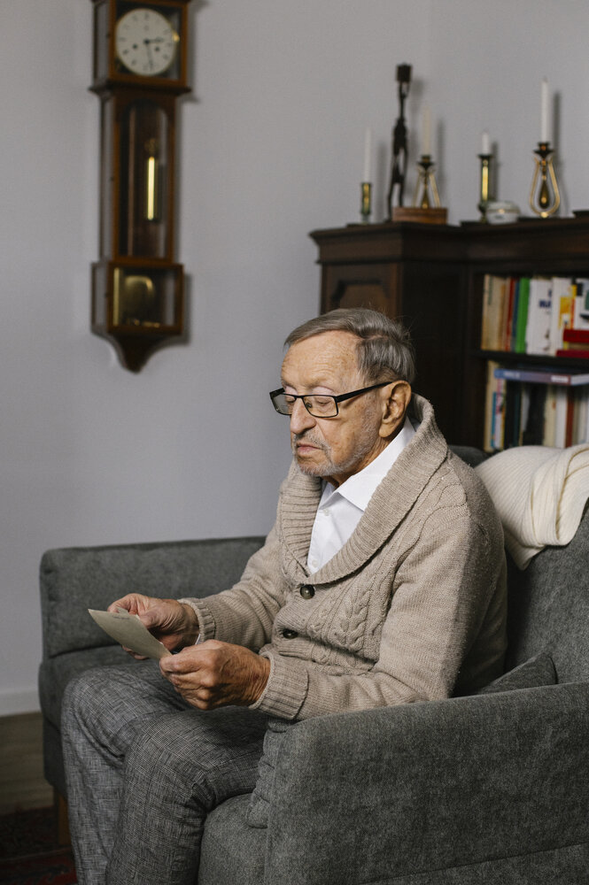 Hans-Jürgen Pickert blickt auf Fotos, die er in seinen Händen hält