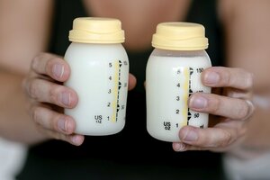 Zwei Hände halten zwei Fläschchen mit Muttermilch
