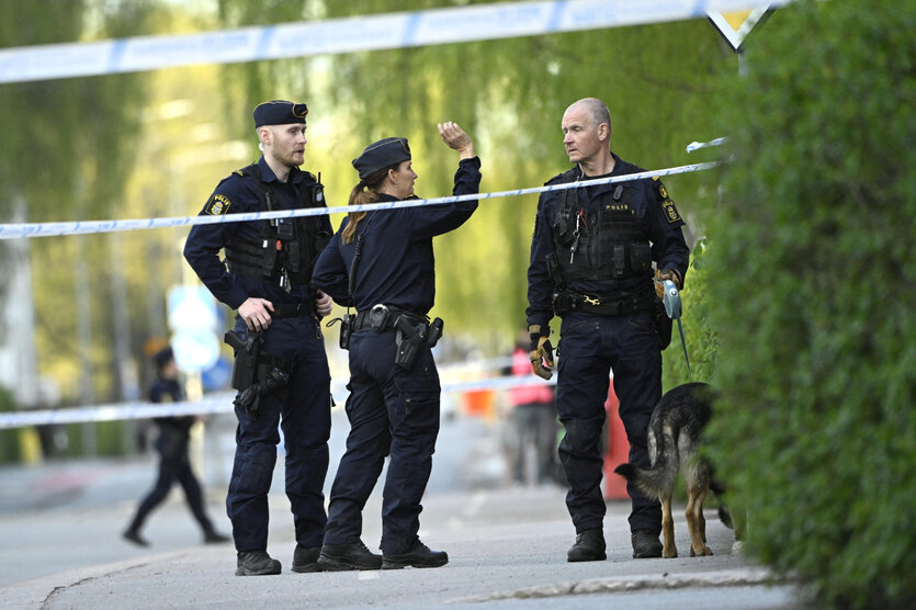 Polizisten stehen hinter Absperrbändern in der Nähe eines Tatorts