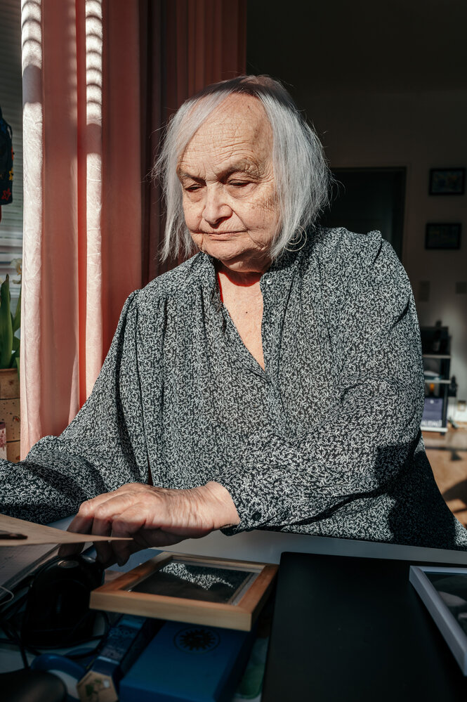 Switlana Petrowskaja schaut auf Fotografiene, die vor ihr ausgebreitet liegen