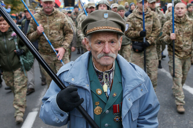 Menschen in historischen Uniformen marschieren eine Straße entlang
