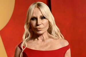 Donatella Versace in einem roten Kleid, langen blonden Haaren und einem ernsten Gesichtsausdruck