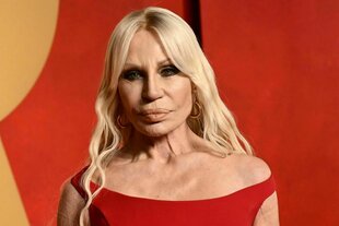 Donatella Versace in einem roten Kleid, langen blonden Haaren und einem ernsten Gesichtsausdruck