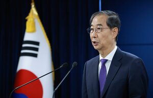 Han Duck Soo an einem Rednerpult vor der koreanischen Fahne