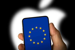 Eine Person hält ein Handy in der Hand. Darauf ist die Europa-Flagge zu sehen. Im Hintergrund ist das Logo von Apple zu erahnen