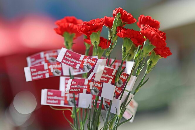Roten Nelken die mit einem Papierschnipsel versehen auf dem steht. Du verdienst mehr 1. Mai