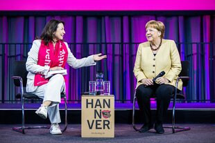 Altkanzlerin Angela Merkel sitzt neben der Kirchentagspräsidentin Anja Siegesmund