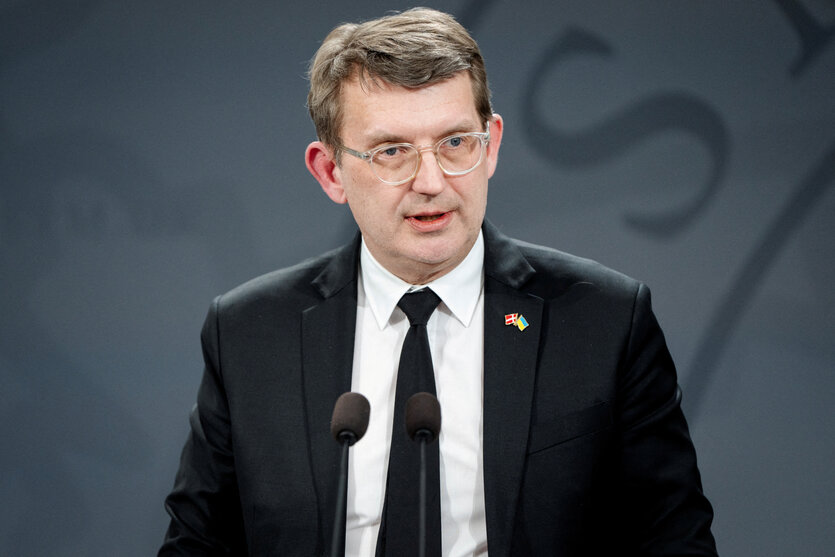 Ein Mann mit schwazem Jacket steht an einem Rednerpult und spricht ins Mikrofon