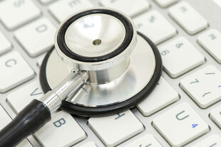 Ein medizinisches Stethoskop liegt auf einer Tastatur
