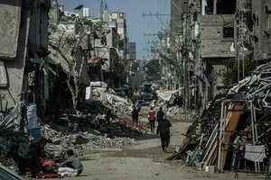 Palästinenser gehen durch ein zerstörtes Wohngebiet in Gaza