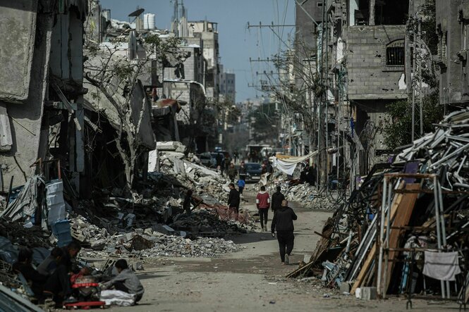Palästinenser gehen durch ein zerstörtes Wohngebiet in Gaza