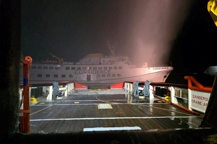 Ein Schiff undeutlich in der Dunkelheit. Rauchschwaden schweben in der Luft