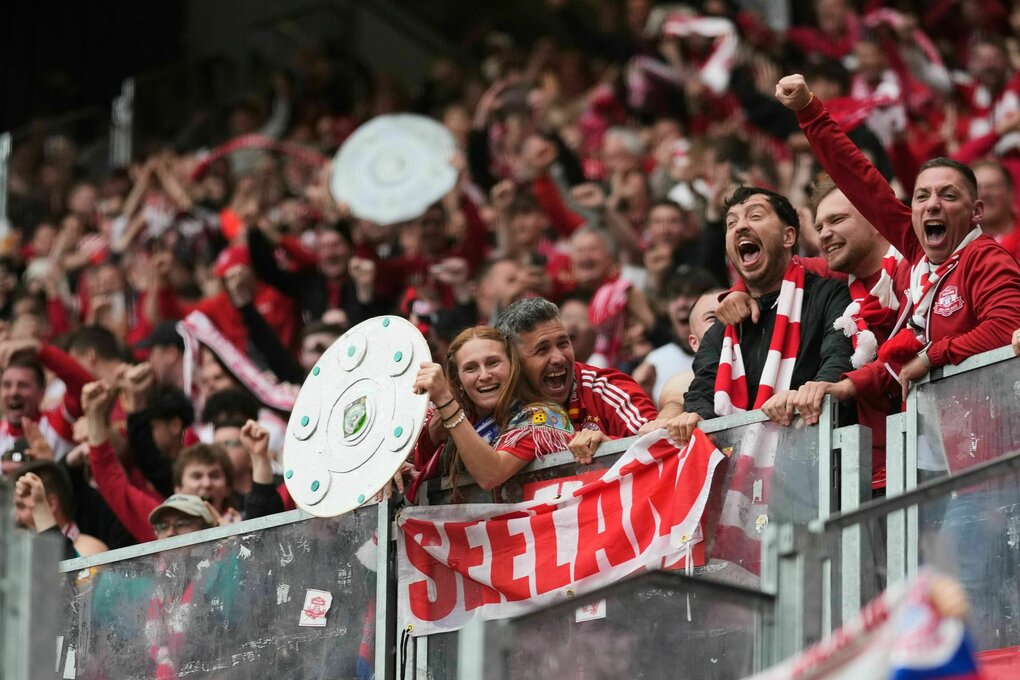 Fans jubeln nach einem Treffer und halten dabei mehrere nachgeahmte Meisterschalen hoch