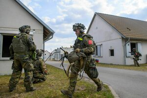 Mit roten Zeichen markierte deutsche Soldaten ziehen sich aus einer Übungsstadt zurück