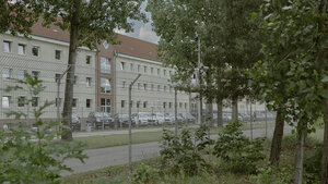 Wohngebäude stehen hinter einem hohen Zaun