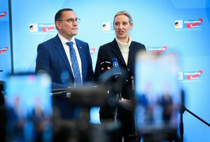 AfD-Chefs Tino Chrupalla und Alice Weidel vor blauem Hintergrund mit AfD-Logos
