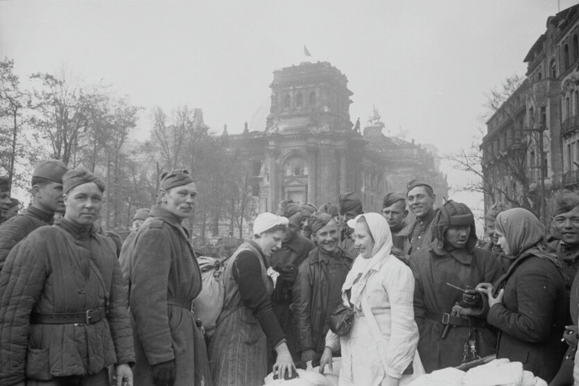 Rotarmisten mit befreiten sowjetischen Frauen unweit des Reichstags, 1945