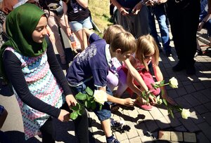 Kinder legen Blumen vor Stolpersteine