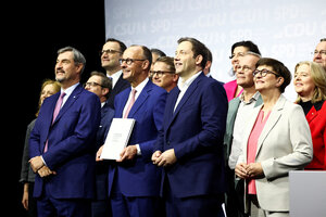 Die neuen Koalitionäre stehen zusammen auf einem Podium, lächeln und Friedrich Merz hält den unterschriebenen in die Kamera