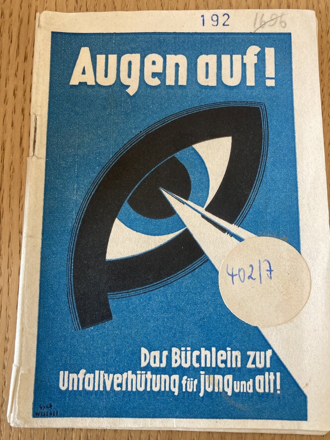 Ein Tarnheft: Grafische Gestaltung, auf blauem Hintergrund ein Auge mit Sehstrahl. auf dem Titel steht: Augen auf ! Das Büchlein zur Unfallverhütung für jung und alt !