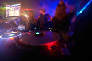 Partygänger tanzen vor einem DJ-Pult