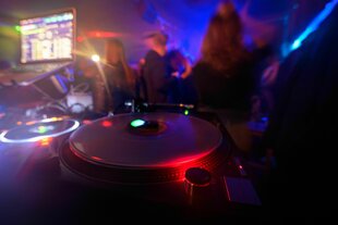 Partygänger tanzen vor einem DJ-Pult