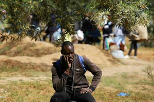Ein Migrant aus Subsahara-Afrika sieht zu, wie ein behelfsmäßiges Lager in al-Amra am Rande der tunesischen Hafenstadt Sfax, in dem er untergebracht war, von den Behörden abgebaut wird.