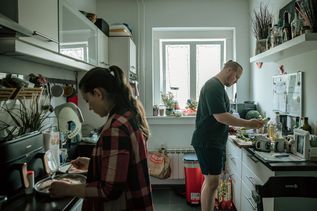 Ein Mann und eine Frau stehen in einer ganz kleinen Küche und bereiten etwas zu