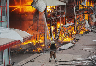 Ein Feuerwehrmann löscht einen Brand in einem Haus nach einem Angriff